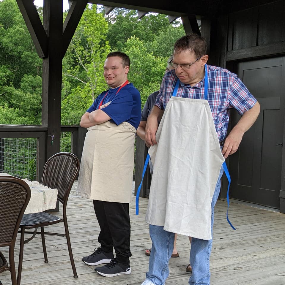 Two men standing next to a table and chairs.