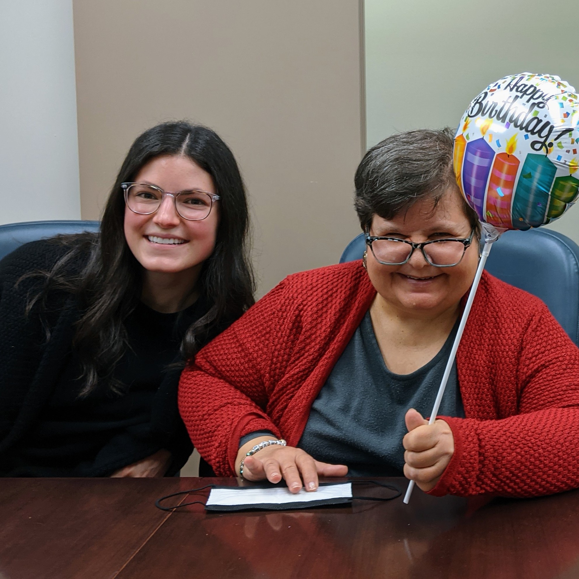 Two women smiling, one is holding a baloon.